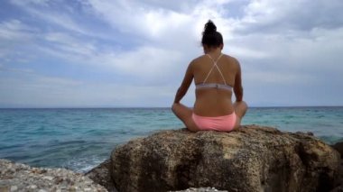 Güzel kadın bir taş üzerinde oturan plaj üzerinde meditasyon yoga egzersiz