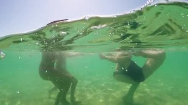Gençleri sıçrama ve su turkuaz deniz gülümseyen içinde oyun, gopro kubbe yarım sualtı görünümü, ağır çekim