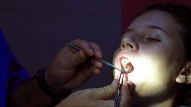 Endodonik diş kanalı başvurusu sırasında dişçide çalışan bir kız.