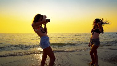 Gün batımında sahilde poz veren mayolu güzel bir manken.