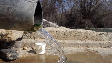 Doğal bir pınar taşradaki bir borudan akar.