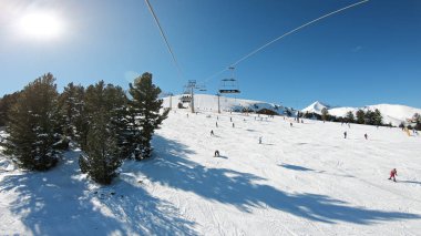 Güneşli bir günde Bulgaristan 'ın Bansko kentindeki Todorka Dünya Kupası kayak merkezinde dağlarda kayak pistleri ve kayak asansörleri olan manzara pov' u.