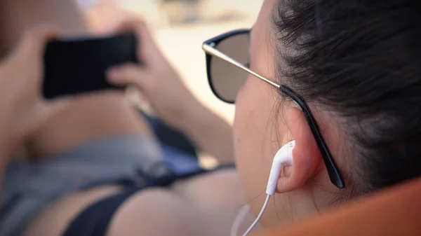Girl listening music on earphones and surf on social media posts, Summer vacation relaxation