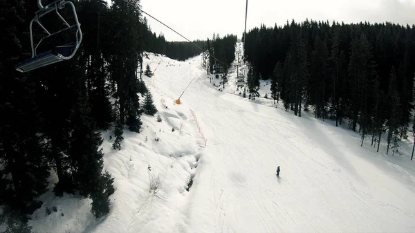 冬の高山スキー場 スキーリフトのPovで雪の森とスキーヤー 空中ビュー スローモーション — ストック写真