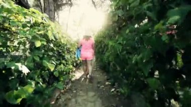 Ormanda ahşap evler kamp amoung dar yeşillik geçit üzerinde plaja yürüyen iki kadın izleme, sinematik steadicam vurdu