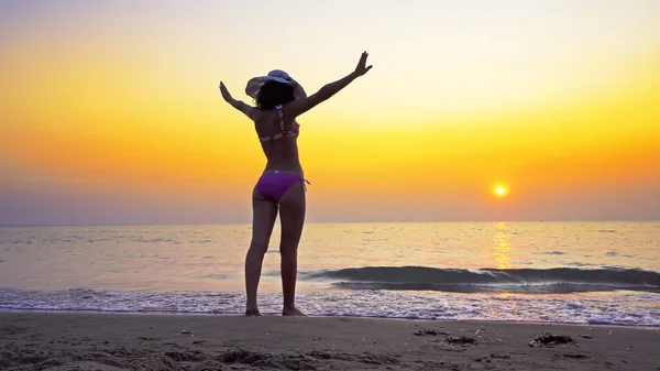 Sexy teen in bikini and hat outstreaching hands wide and enjoy sea sunset, Summer vacation freedom concept