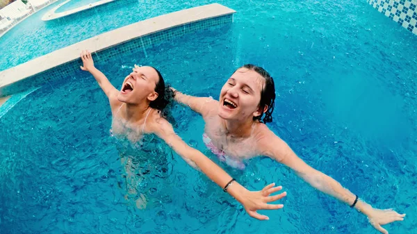 Girls smile and laughs in the rain during summer vacation in swimming pool. Rain falls, the drops fall on their face and the girls are happy with life and nature around. concept of happy life, slow motion