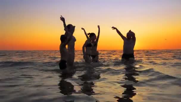 年轻的有趣的聚会的人跳舞和喷洒在海滩日落 — 图库视频影像