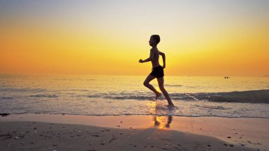 Koşma, günbatımı karşı deniz sahilde koşu genç çocuk closeup