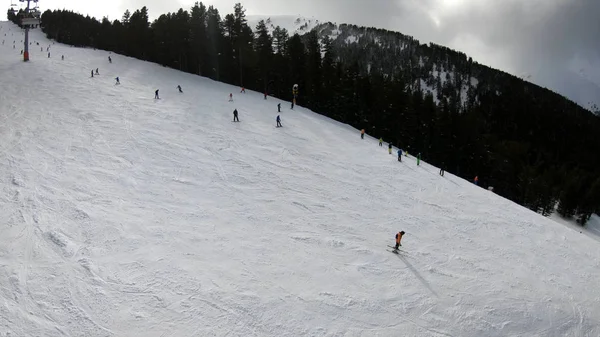 滑雪者和滑雪者在滑雪场下坡 在一个滑雪胜地 在晴朗的天空下 在雪林 滑雪缆车和山的背景下 波夫慢动作 — 图库照片