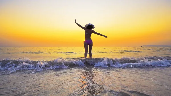 모자를 해변을 산책하는 소녀가 자유를 만끽하고 소녀가해 들어간다 — 스톡 사진