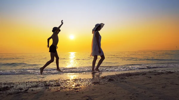 Tourism and travel vacation. Adorable family having fun on beach against sunset. Mother and son walk on beach an play, cinematic steadicam shot