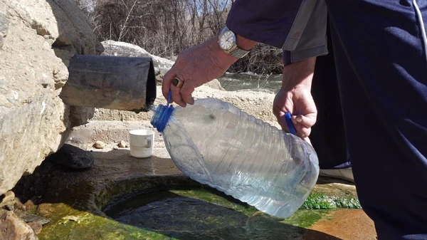 5 litre plastik su şişesiyle doğal kaynak suyu toplamak.