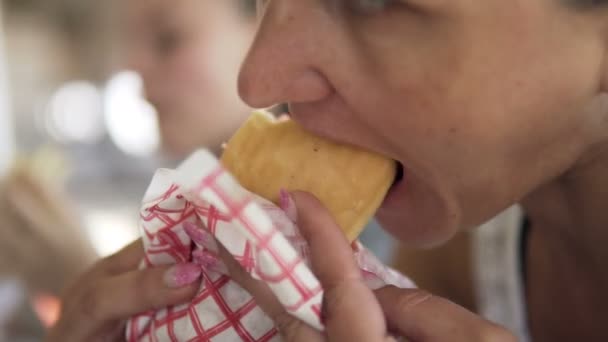 若い女性が昼食時にドナーケバブを食べているおいしいジューシーなシャワルマをかむ ファーストフードのコンセプト — ストック動画