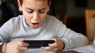 Bir oyunu kazanmak. İle açılan ağız ve ellerini smartphone üstünde oyun kazanmak kutluyor mutlu çocuk bakarak şok