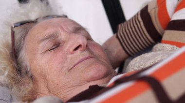 Açık havada salıncakta oturan düşünceli üzgün yaşlı kadın