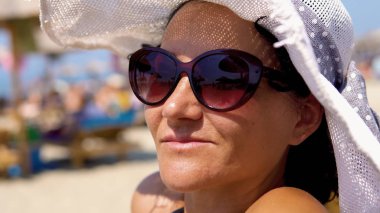 Şapka ve güneş gözlüğü giyen genç yaz seksi kadın yüzü close-up. Açık havada yaşam tarzı portre