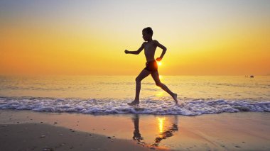 Koşma, günbatımı karşı deniz sahilde koşu genç çocuk closeup