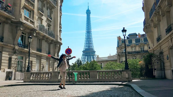 Yürüme ve yükselen Camoens Avenue Caddesi atlama mutlu kadın Paris, geleneksel Paris binalar ve mahalle arka planda Eyfel Kulesi ile geniş açık eller