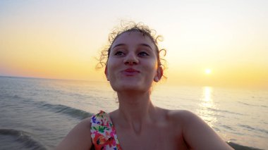 Gün batımında kumsala dönen ve elinde kamera olan gençlerin selfie 'si.