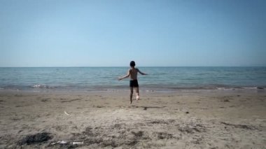 Deniz suyu, ağır çekim bir plajda çalışan küçük çocuk