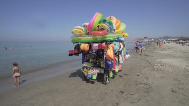 Homem Monta Loja Móvel Vendendo Brinquedos Para Criança Praia Filmado — Vídeo de Stock