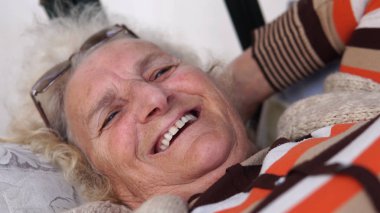 Sundurma salıncak üzerinde rahat yalan gülümseyen yaşlı kadın kıdemli. Sinematik sığ dof