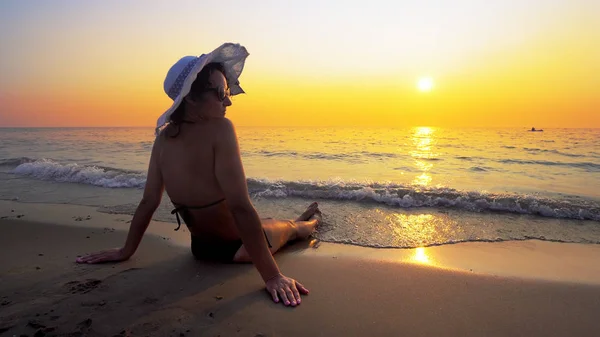 Hispanic Woman Hat Sitting Beach Sunset Sea Waves Splash Her — Stock Photo, Image