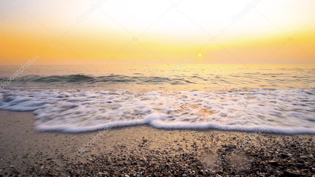 Amazing background from sea waves splashing beach sand at sunset