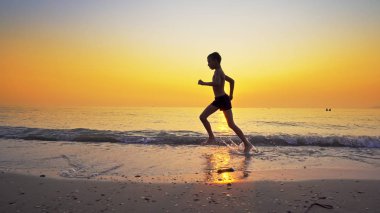 Koşma, günbatımı karşı deniz sahilde koşu genç çocuk closeup
