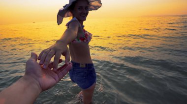 Romantik güzel kız sahilde birlikte yaz aylarında gülen adam, elini tutarak mayo ve şapka giriyor seyahat tatil tatil, tatil veya Sevgililer kavramı tatil