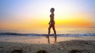 Dalgalar deniz günbatımı sıçramasına su kumsalda yürüyüşüne uygun kadın