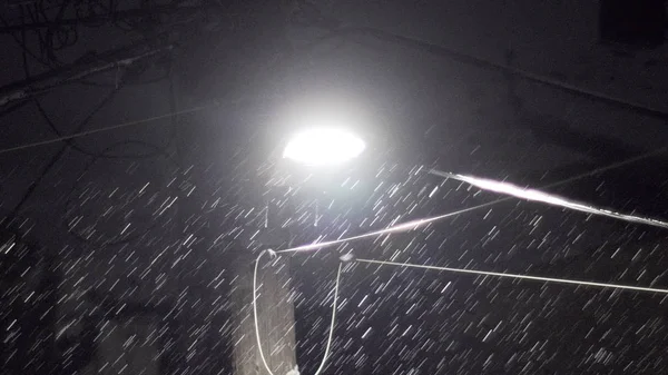 Led ライト電気ケーブル ワイヤ インスタレーションを通りの下の暗い夜に密な雪片 — ストック写真