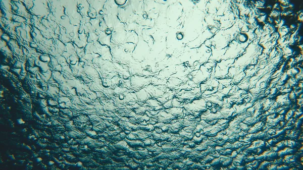 Rain drops in the pool water, underwater view