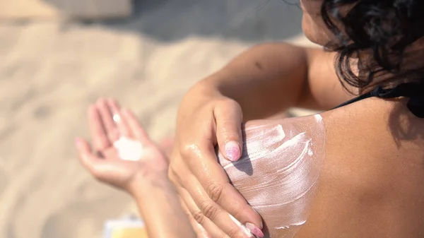 Modello Femminile Applicare Crema Solare Sulla Mano Sulla Spalla Seduto — Foto Stock