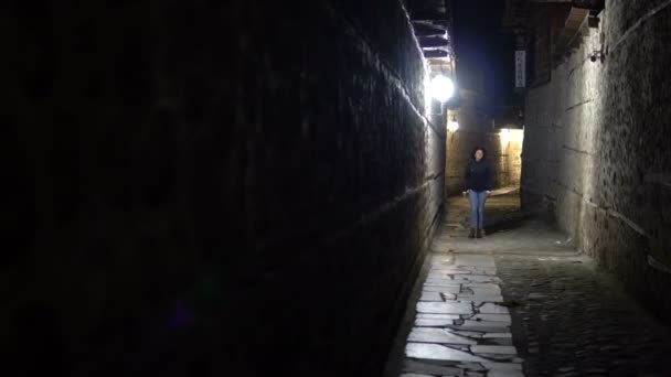 Osamělá žena chůze v staré kamenné dlažbě uličce v noci v zadní ulici