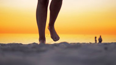 Genç Latin Amerikalı kız okyanus plaj tarafından günbatımında yürüyüş çıplak bacaklar ayak