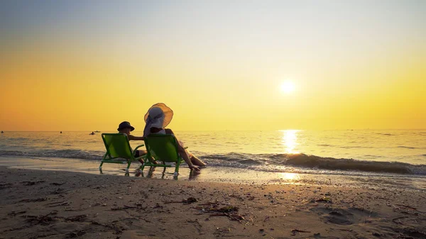 Mor Søn Med Hat Siddende Strandstole Kigger Den Nedgående Sol - Stock-foto