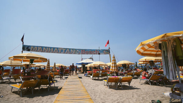 Durres, Albania - 10 Aug, 2017: Tourist people visiting famous Manhattan beach during summer vacation, cinematic crane shot