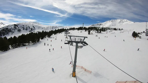 滑雪者和滑雪者在滑雪场下坡 在一个滑雪胜地 在晴朗的天空下 在晴朗的天空下 慢动作 滑雪场 在滑雪场上 有雪林 滑雪缆车和山 — 图库照片