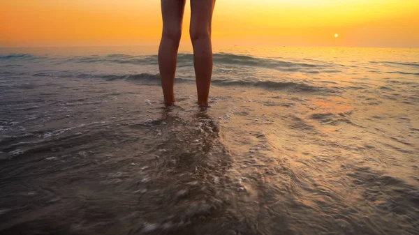 海滩夕阳西下 女人的脚被海浪拍打着 平静悠闲的大海洒落在美丽的海滩上 — 图库照片