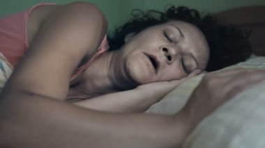 Genç bir kadın yatakta uzanıyor, uykusundan uyanıyor ve esniyor.