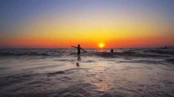日落时分 男孩在海滩上慢慢地跑出了水面 拍摄了一部稳定的电影 — 图库视频影像