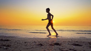 Koşma, günbatımı karşı deniz sahilde koşu genç çocuk closeup