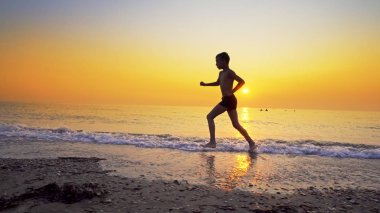 Koşma, günbatımı karşı deniz sahilde koşu genç çocuk closeup