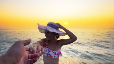 Romantik güzel kız sahilde birlikte yaz aylarında gülen adam, elini tutarak mayo ve şapka giriyor seyahat tatil tatil, tatil veya Sevgililer kavramı tatil