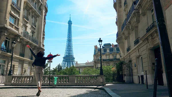 Yürüme ve yükselen Camoens Avenue Caddesi atlama mutlu kadın Paris, geleneksel Paris binalar ve mahalle arka planda Eyfel Kulesi ile geniş açık eller