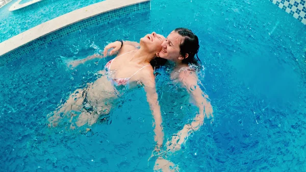 Girls smile and laughs in the rain during summer vacation in swimming pool. Rain falls, the drops fall on their face and the girls are happy with life and nature around. concept of happy life, slow motion
