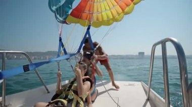İki kız giymek Sefety kemer önce Parasailing uçuş paraşüt yat tekne ile yaz deniz üzerine çekti çıkar 