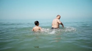 İki kişi, baba ve oğul aile oynamak deniz su sıçramasına